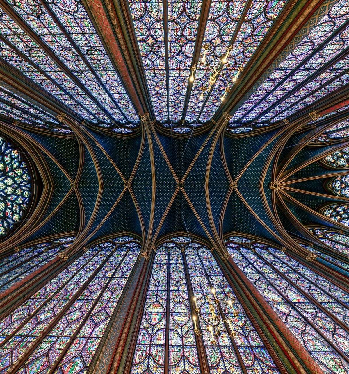 Intricate stained glass ceiling of Sainte Chapelle in Paris displaying Gothic architecture.