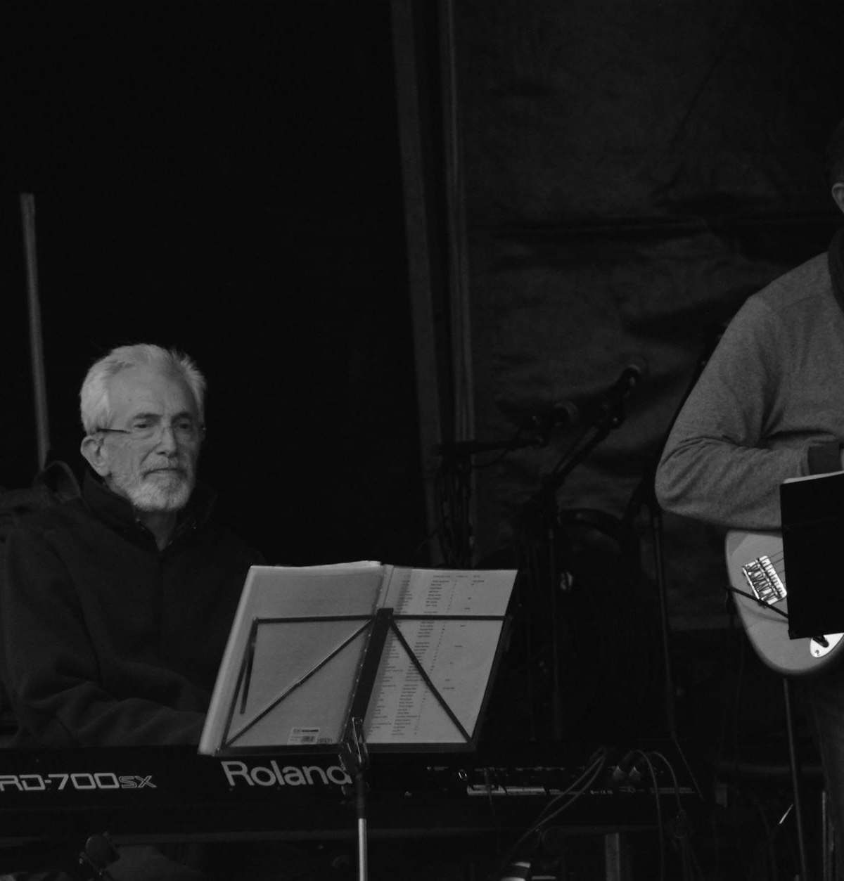 Jazz musicians performing with piano and guitar in a moody stage setting.