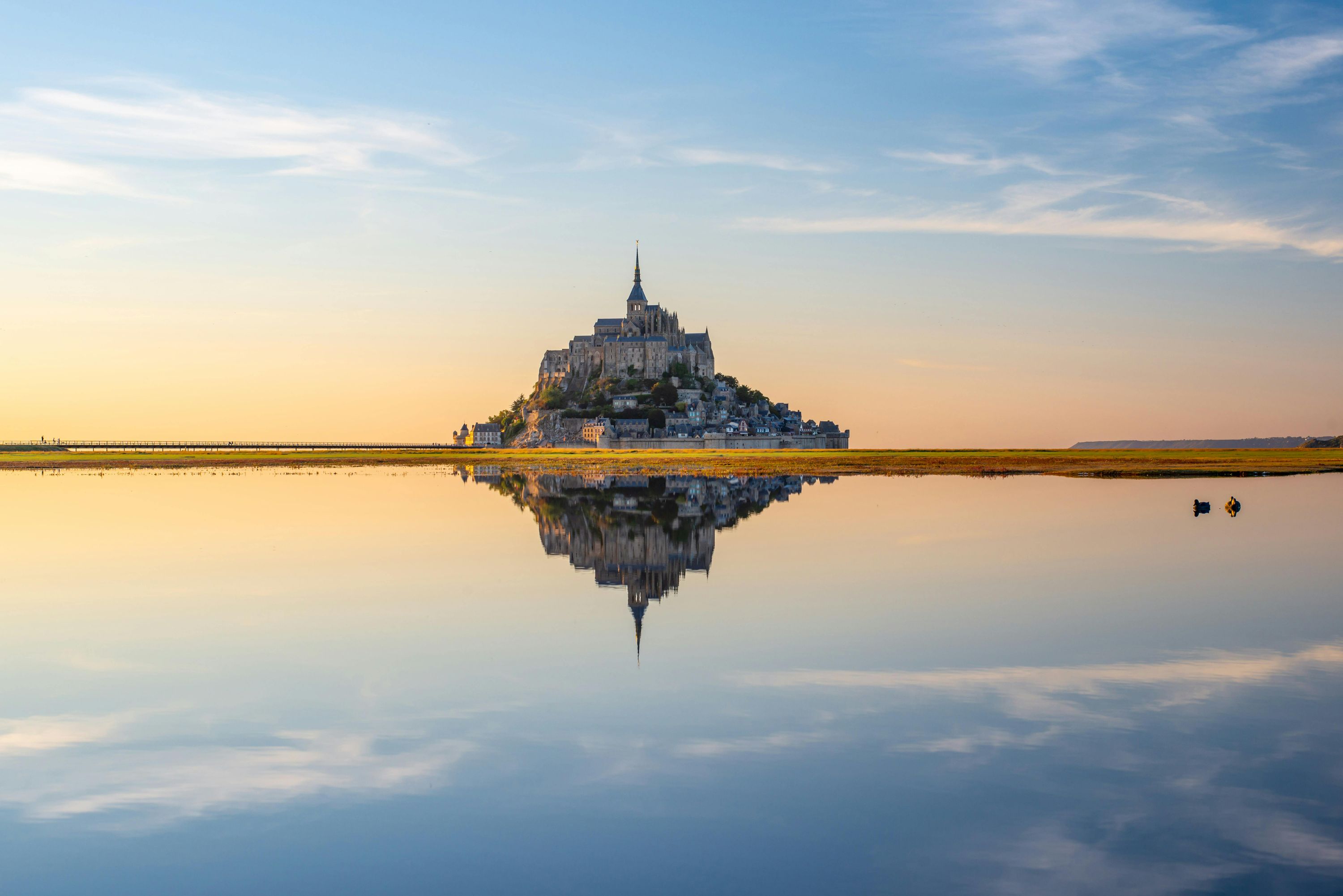 Majestic Mont Saint-Michel abbey at golden sunset with reflections in the bay, Normandy, France - France tours