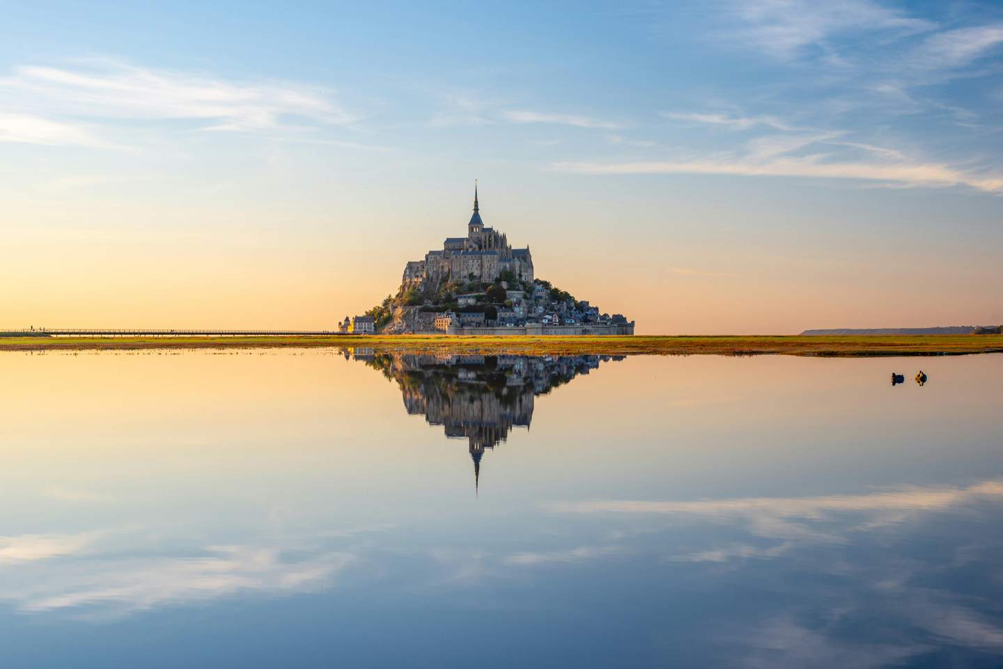 Majestic Mont Saint-Michel abbey at golden sunset with reflections in the bay, Normandy, France - France tours