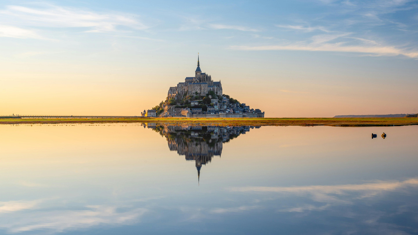 Majestic Mont Saint-Michel abbey at golden sunset with reflections in the bay, Normandy, France - France tours