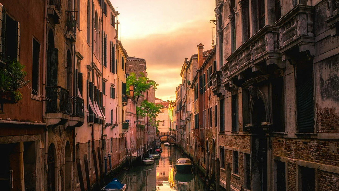 Serene view of Venice canal with gondola at golden sunset, Venice, Italy